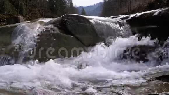 山溪和石急流与雪水的快速流动冬天的瀑布慢动作视频的预览图