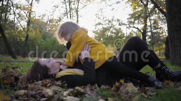 家庭散步可爱的小女孩和她迷人的年轻母亲的肖像在秋天公园玩得很开心视频的预览图
