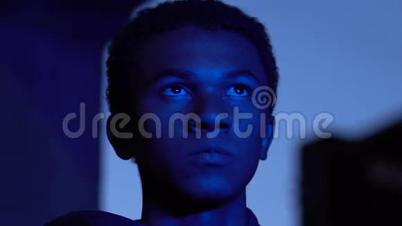 穿着蓝色城市灯的美国黑人男性少年孤独的概念视频的预览图