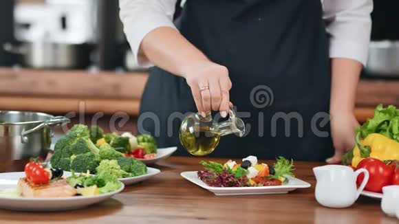 围裙女厨师的手把橄榄油倒在新鲜蔬菜的混合物上4k红色摄像机特写镜头视频的预览图