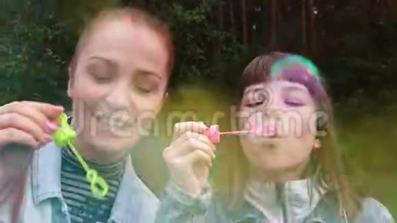 一个年轻的女人和她的女儿在一个夏天的晚上母亲节在公园里吹泡泡家庭关系视频的预览图