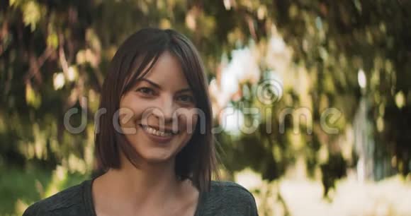 黑发女人在户外微笑的肖像在电影院摄像机上用4K镜头拍摄视频的预览图
