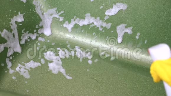 用白色泡沫洗涤剂把黄色手套喷进绿色闪闪发光的浴缸里视频的预览图