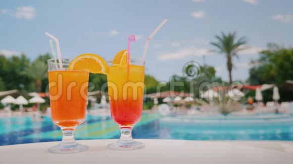 池和棕榈树的背景上两杯清凉的鸡尾酒立在桌上天堂和豪华度假胜地视频的预览图