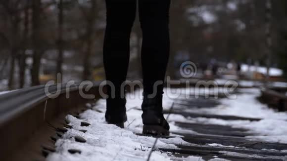 一个女孩的腿在冬天沿着旧铁路轨道行走慢动作视频的预览图