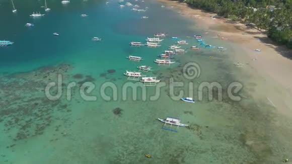 无人驾驶飞机俯视着泻湖蔚蓝水面上的传统菲律宾船只带蓝色海湾的海景视频的预览图