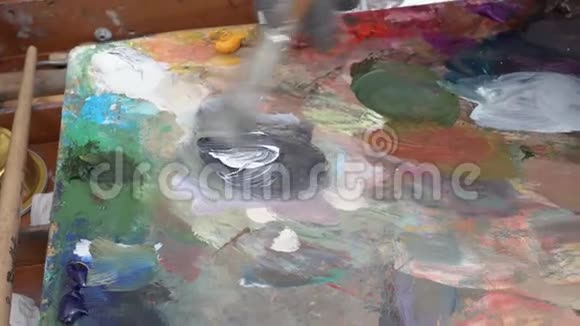 创意画家将油画颜料的调色板混合在画架上近距离观看视频的预览图