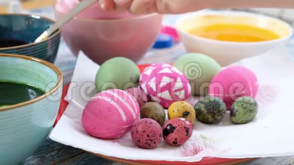 把女人的手用鸡蛋染色复活节彩蛋五颜六色的复活节彩蛋复活节的筹备工作视频的预览图