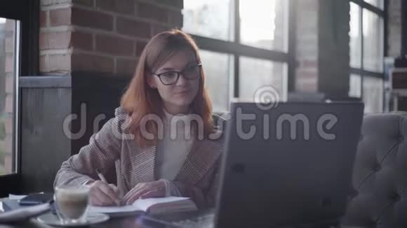 互动教育年轻女孩眼镜专家在笔记本电脑上上网学习坐在桌子上视频的预览图