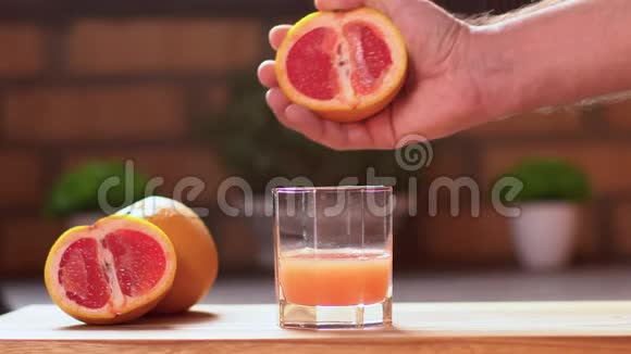 一个面目全非的男人挤了一半成熟多汁的柚子新鲜柑橘汁掉下来视频的预览图