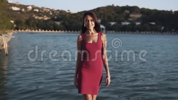 女人走在码头上微笑着山和湖在背景上慢动作视频的预览图