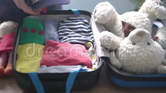 一个女人小心翼翼地把孩子东西用手提箱叠起来视频的预览图