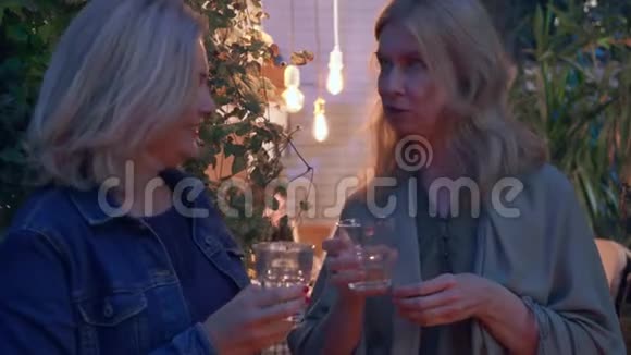 两个金发成熟的女人聊天喝酒邻居在夏天晚上闲聊友谊的概念视频的预览图