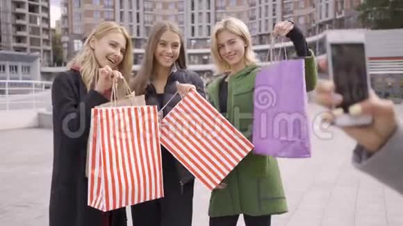 高加索女人拿着购物袋给她的三个朋友拍照四位时尚女性在购物后休息女孩视频的预览图