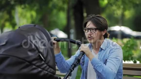 没有经验的年轻父亲紧张地摆动婴儿车在城市公园视频的预览图