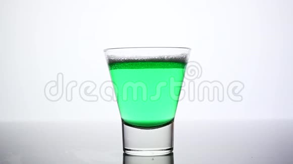 冰块掉进盛满绿色白酒的玻璃杯里视频的预览图