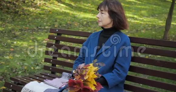 在市中心公园的秋天一位年长的妇女坐在长凳上丈夫给妻子端来一杯热茶视频的预览图