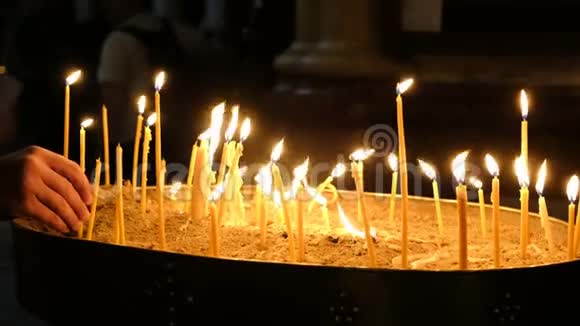 女孩在黑暗中把蜡烛放在教堂里放在人们的背景下沙烛台视频的预览图
