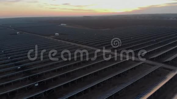 空中无人机在日落时进入太阳能农场的大型太阳能电池板太阳能电池发电厂录像4K视频的预览图