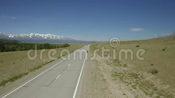年轻的女徒步旅行者背着背包戴着帽子在山间山谷的公路上行走欣赏着山峦的景色女人迷惘视频的预览图