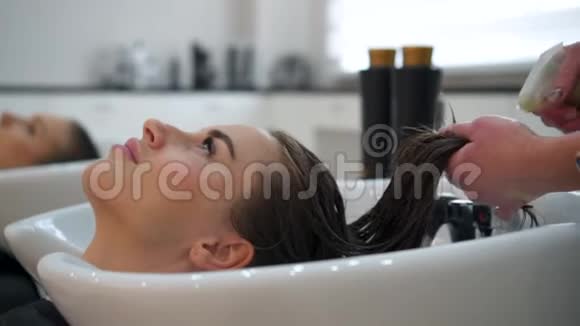 理发师将头发油涂在女性头发的末端视频的预览图