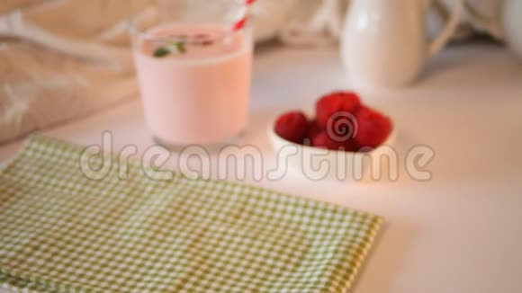 女人的手放在桌子上玻璃杯里是天然自制的酸奶和新鲜的覆盆子早餐概念视频的预览图
