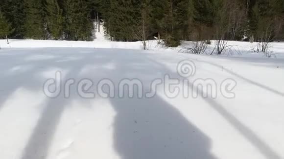阳光明媚的一天一个背着背包的男人在雪地里的影子视频的预览图