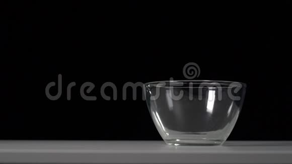 香甜蓬松的焦糖爆米花倒入白色桌子上透明的班级碗中视频的预览图