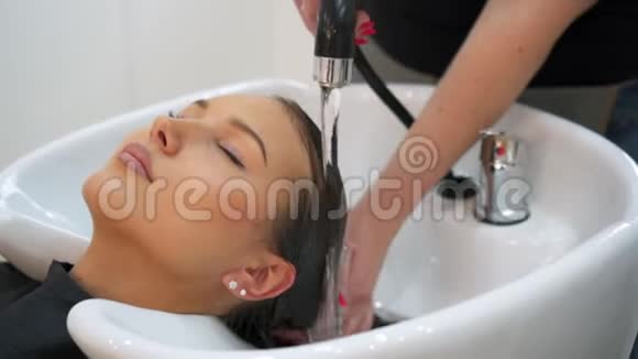 理发师一边闭着眼睛一边给女人洗头视频的预览图