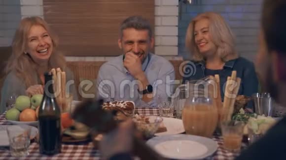 一群成熟的人谈笑风生地坐在桌边幸福的家庭聚集在一起庆祝节日视频的预览图