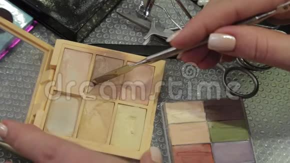 专业化妆师在调色板上拿起一个铁铲霜用于面部视频的预览图