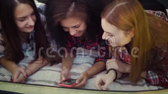 快乐的女孩在毯子上放松用智能手机娱乐视频的预览图