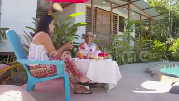 两位女士在酒店的泳池边享用热带早餐视频的预览图