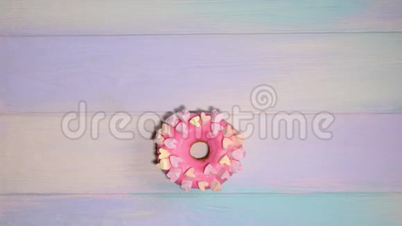 女人的手在彩虹的背景上用字母在粉红色的甜甜圈上传播甜甜圈视频的预览图