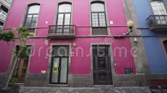 一个年轻的女人在一个五彩缤纷的西班牙城市里玩得很开心走过一座美丽的粉红色建筑大角度冒险视频的预览图