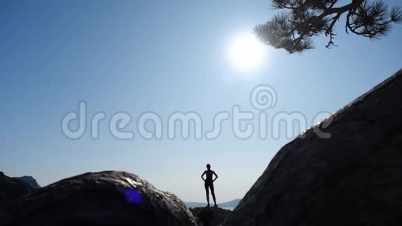 自信的年轻女子在日出时缓慢地向山顶走去一位女士徒步旅行的剪影视频的预览图