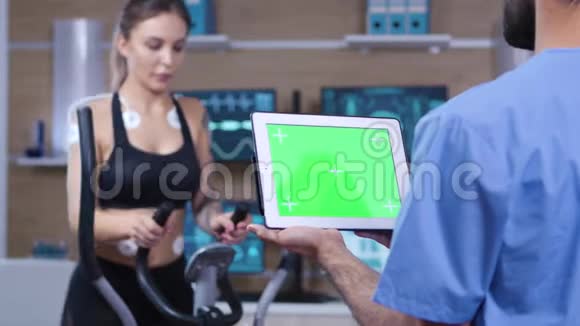 医生在运动员面前拿着绿色屏幕的平板电脑视频的预览图