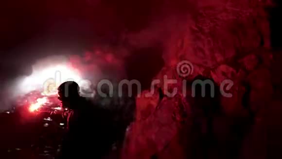 孤独的男人带着红色的燃烧信号在黑暗的洞穴里寻找洞旅游的概念库存录像男性视频的预览图