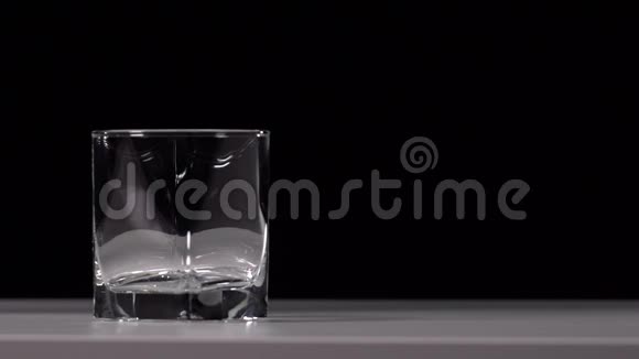 在黑色背景的白色桌子上将水倒入透明玻璃的工作室镜头视频的预览图