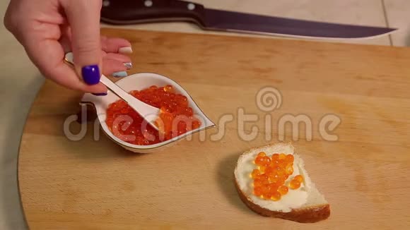 一只雌性手用鱼子酱涂上一个红色鱼子酱三明治视频的预览图