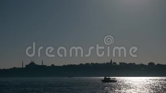 黄昏时分船帆在波光粼粼的海面上映衬着城市的轮廓视频的预览图