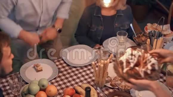 一群人坐在桌子旁庆祝节日女人把蛋糕给男人他把盘子放在桌子上视频的预览图