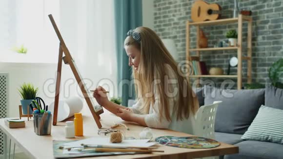 快乐的学生在家里绘画画笔和调色板可以在桌子上看到视频的预览图