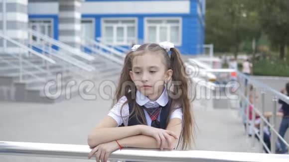 肖像拍摄的悲伤的小女孩穿着校服在学校的院子里反对建造一所小学视频的预览图