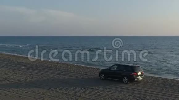 沿着海边沙滩行驶的汽车的鸟瞰图视频的预览图