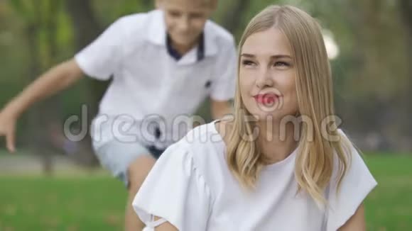 美丽的白种人女人坐在公园里看着远处微笑着两个孩子朝她跑来拥抱视频的预览图
