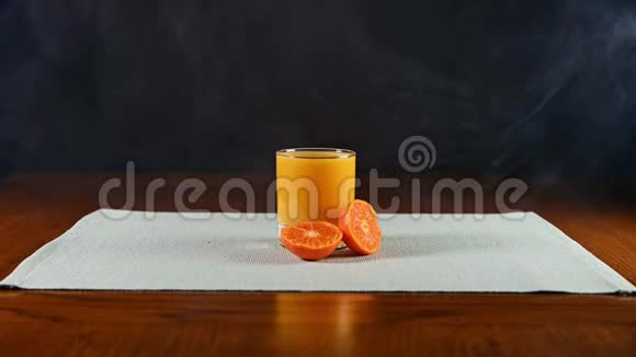 孤立的一杯橙汁被切成薄片的橙子挤着烟雾掠过视频的预览图