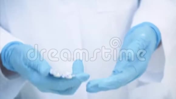 医生的手穿着医用一次性手套从水泡包中取出白色药丸视频的预览图