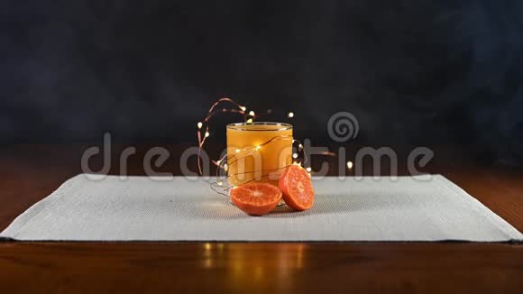 被仙女的灯光和切成片的橘子挤上一杯孤立的橙汁视频的预览图