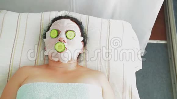 一位男性美容师把新鲜黄瓜放在水疗沙龙客户的脸上视频的预览图